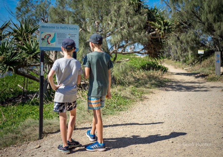 boys looking at hells gate sign at Noosa